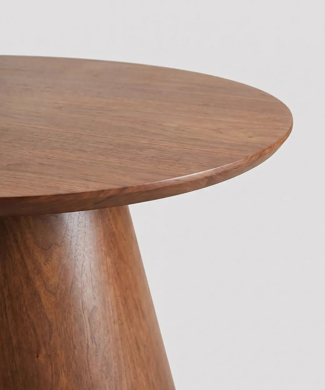 Detalle de superficie y base cónica de mesa Arure en madera nogal oscuro con diseño contemporáneo elegante.