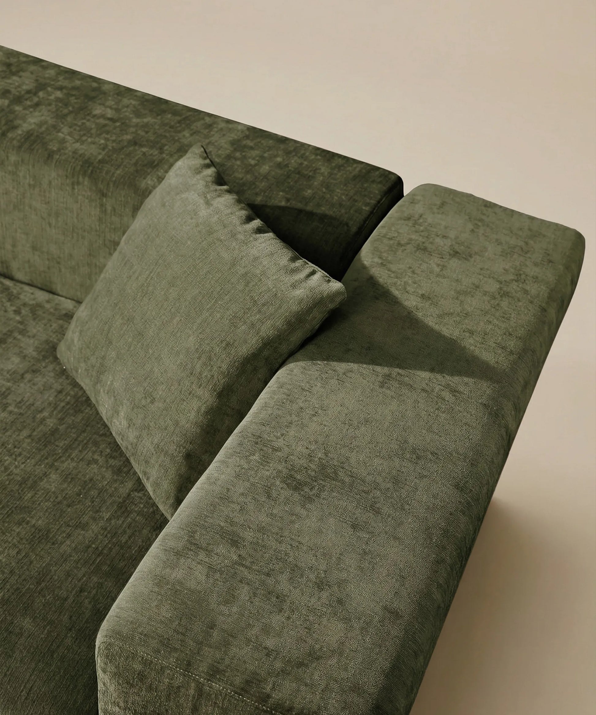 Detalle del sofá Naos en tono verde, con textura suave y cojín a juego para mayor confort y estilo robusto.