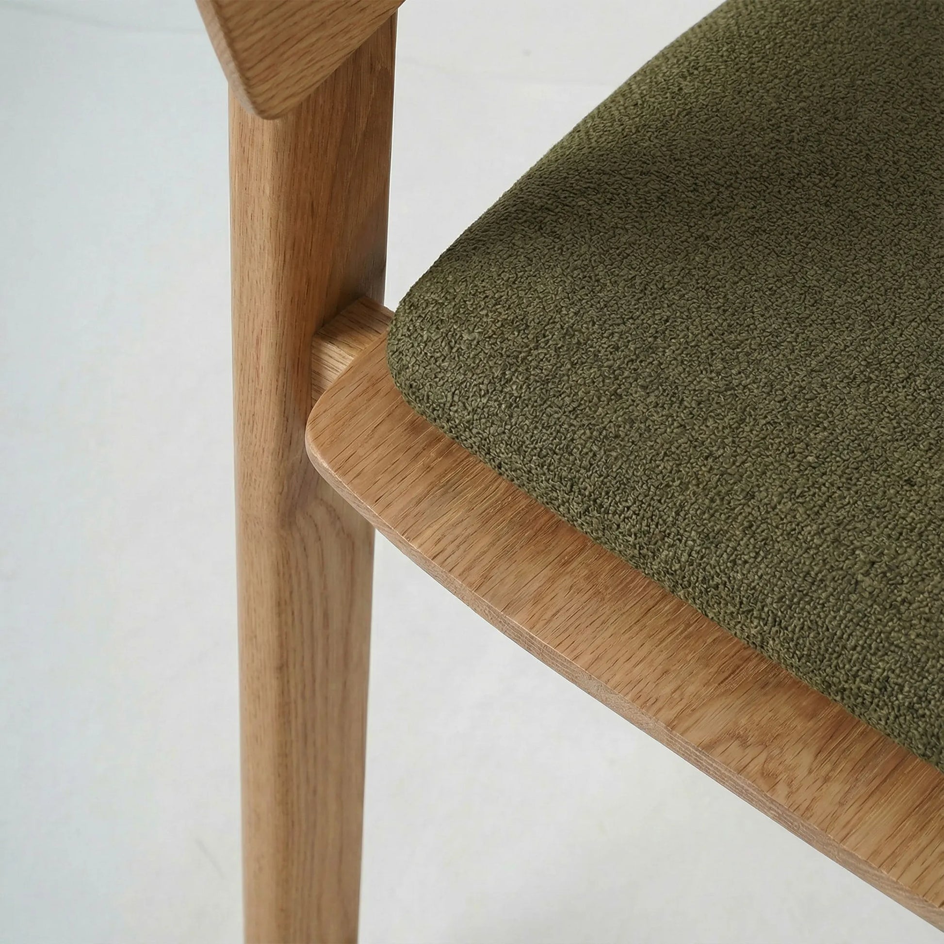 Silla Sabina de diseño contemporáneo en madera de fresno con asiento tapizado en tono verde suave.