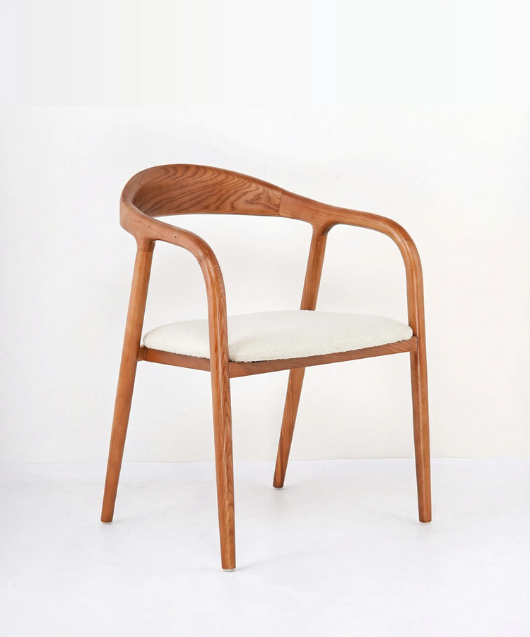 Silla de comedor Tabaiba en madera de fresno con diseño orgánico y asiento tapizado en tono claro.