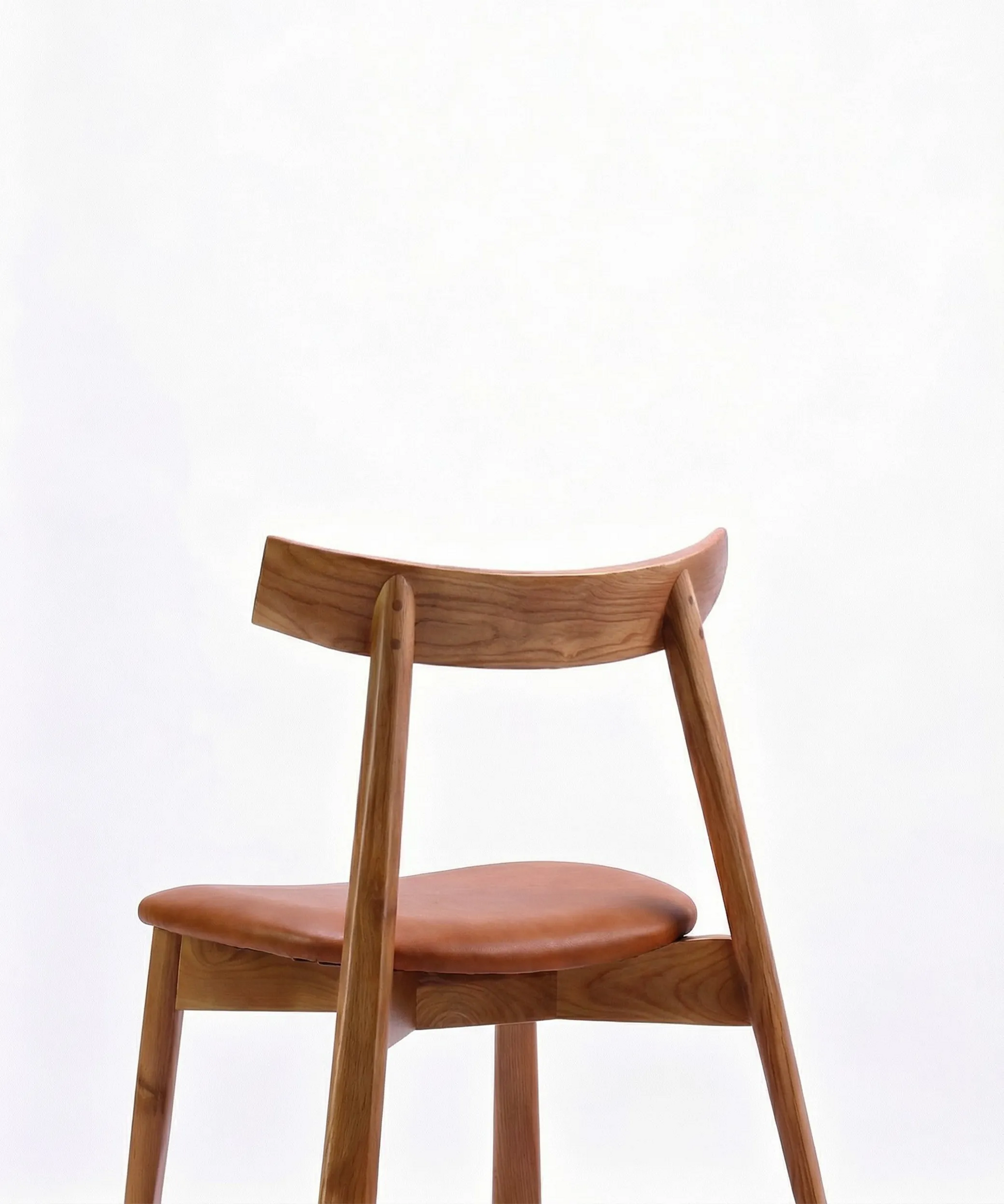 Silla Magarza de comedor en madera de fresno tono café con asiento tapizado en diseño contemporáneo y curvas suaves.