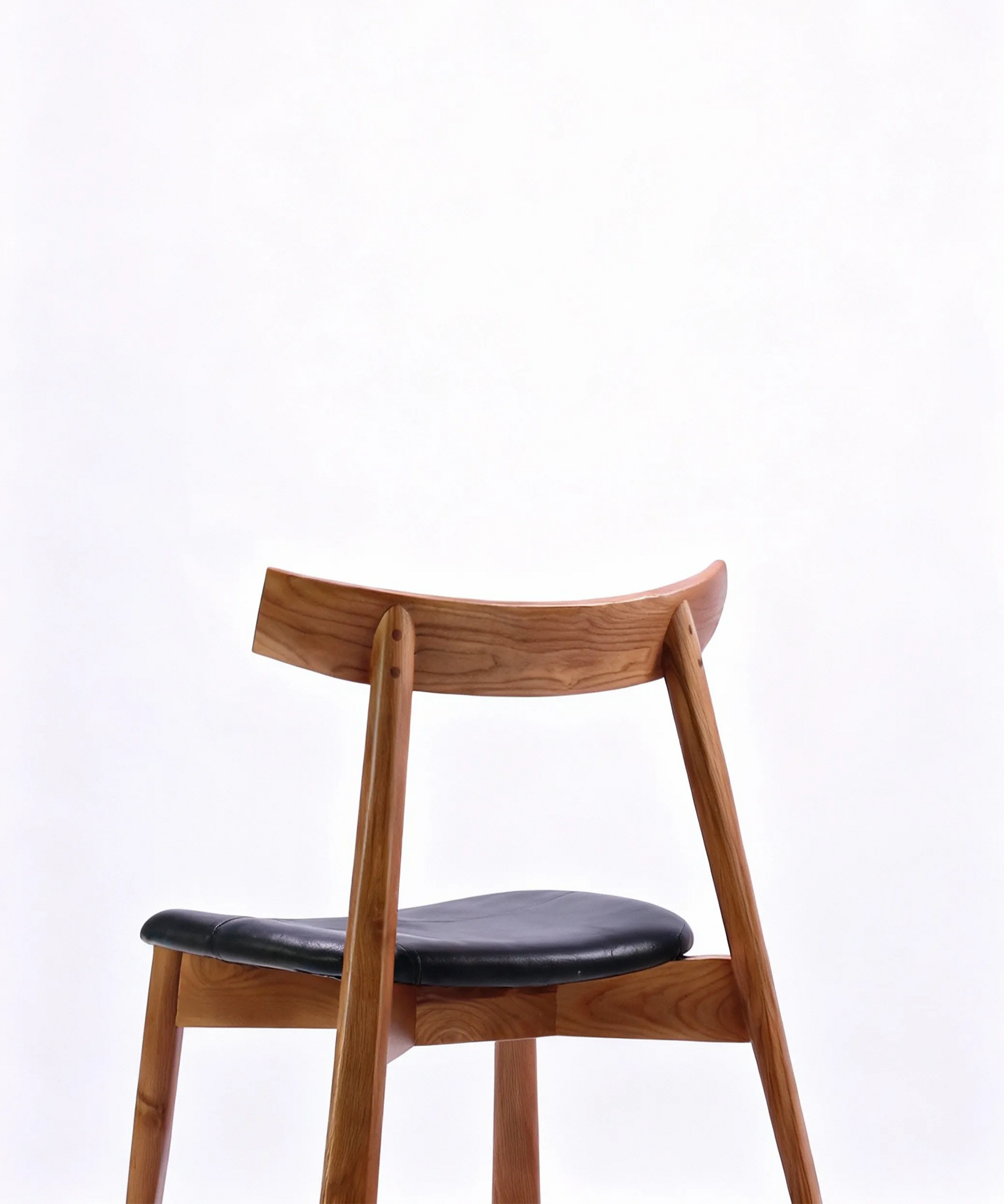 Silla Magarza de comedor en madera de fresno café con asiento acolchonado negro y diseño contemporáneo elegante.