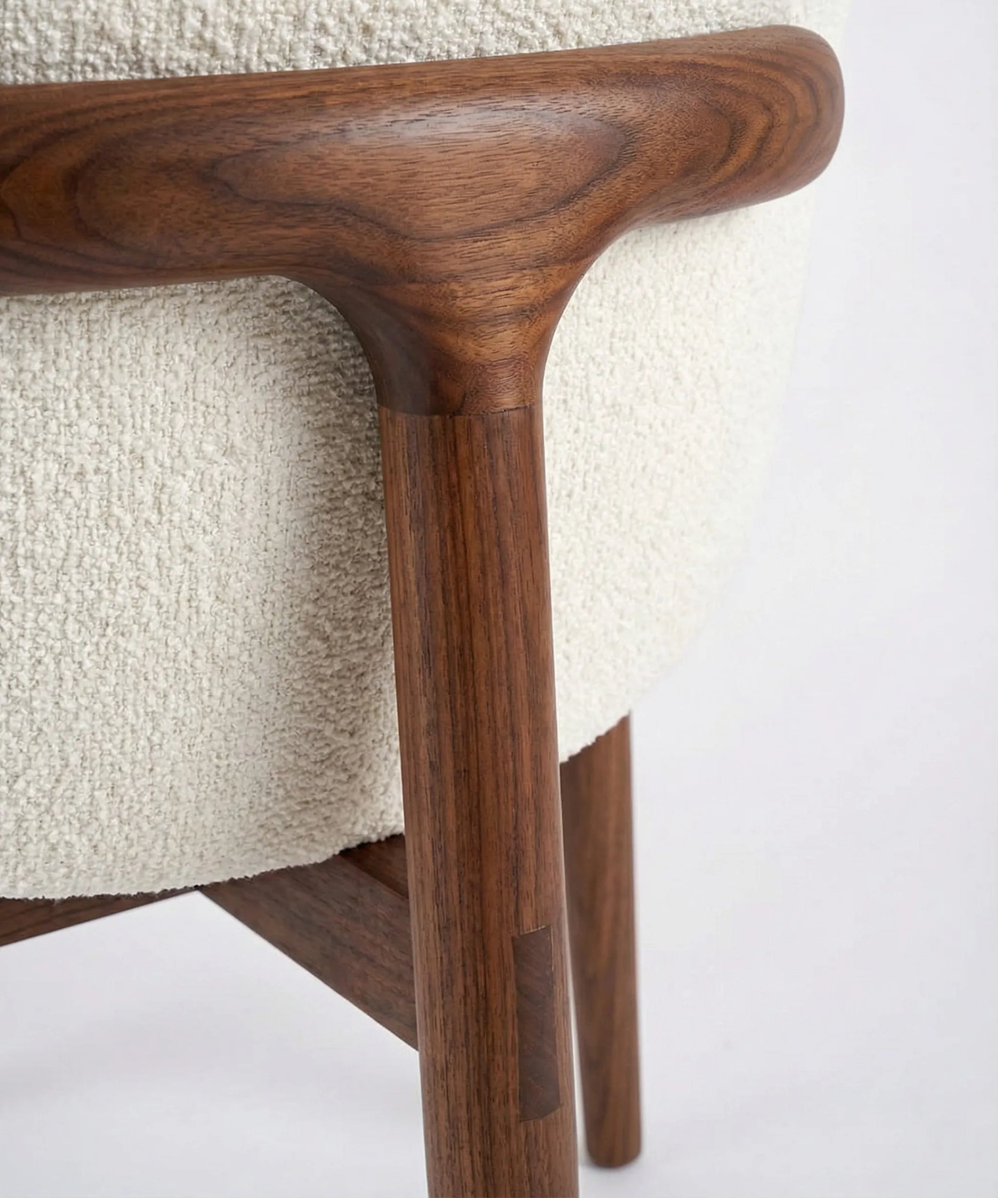 Detalle de madera de fresno en estructura de silla Laurisilva con tapicería clara y líneas suaves y envolventes