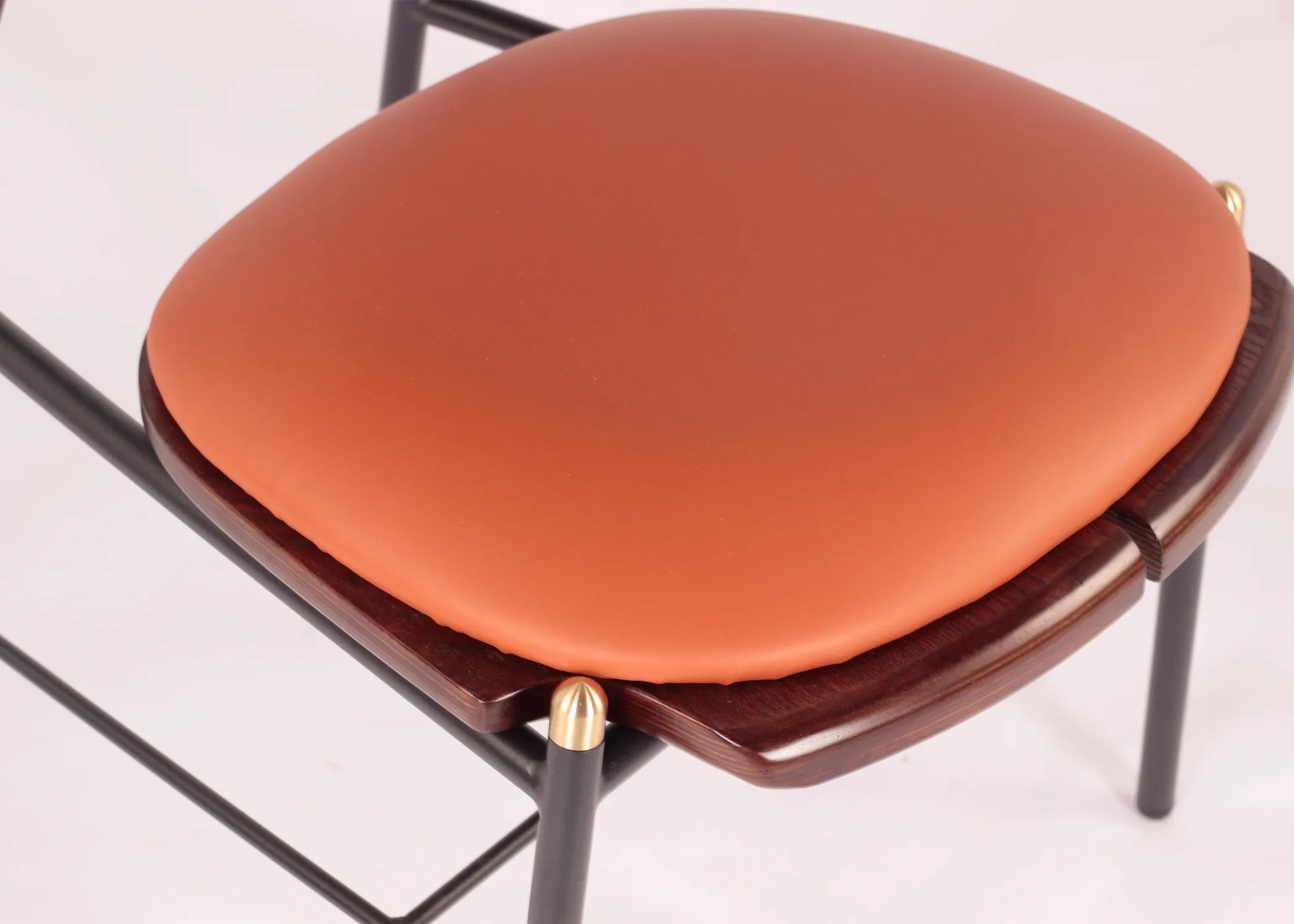 Silla Mocán con asiento acolchonado en tono terracota, estructura metálica negra y detalles en madera oscura.