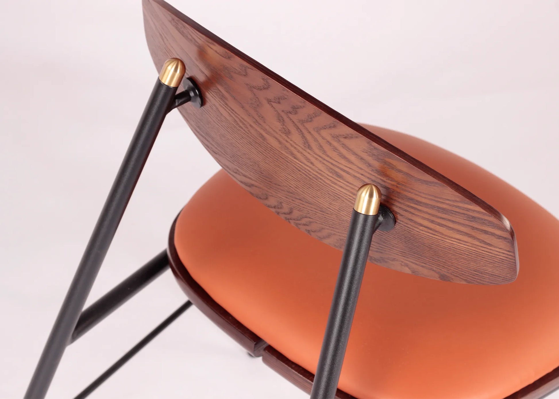 Silla Mocán con respaldo de madera de fresno y estructura metálica negra, asiento en tono cálido ideal para comedor moderno.