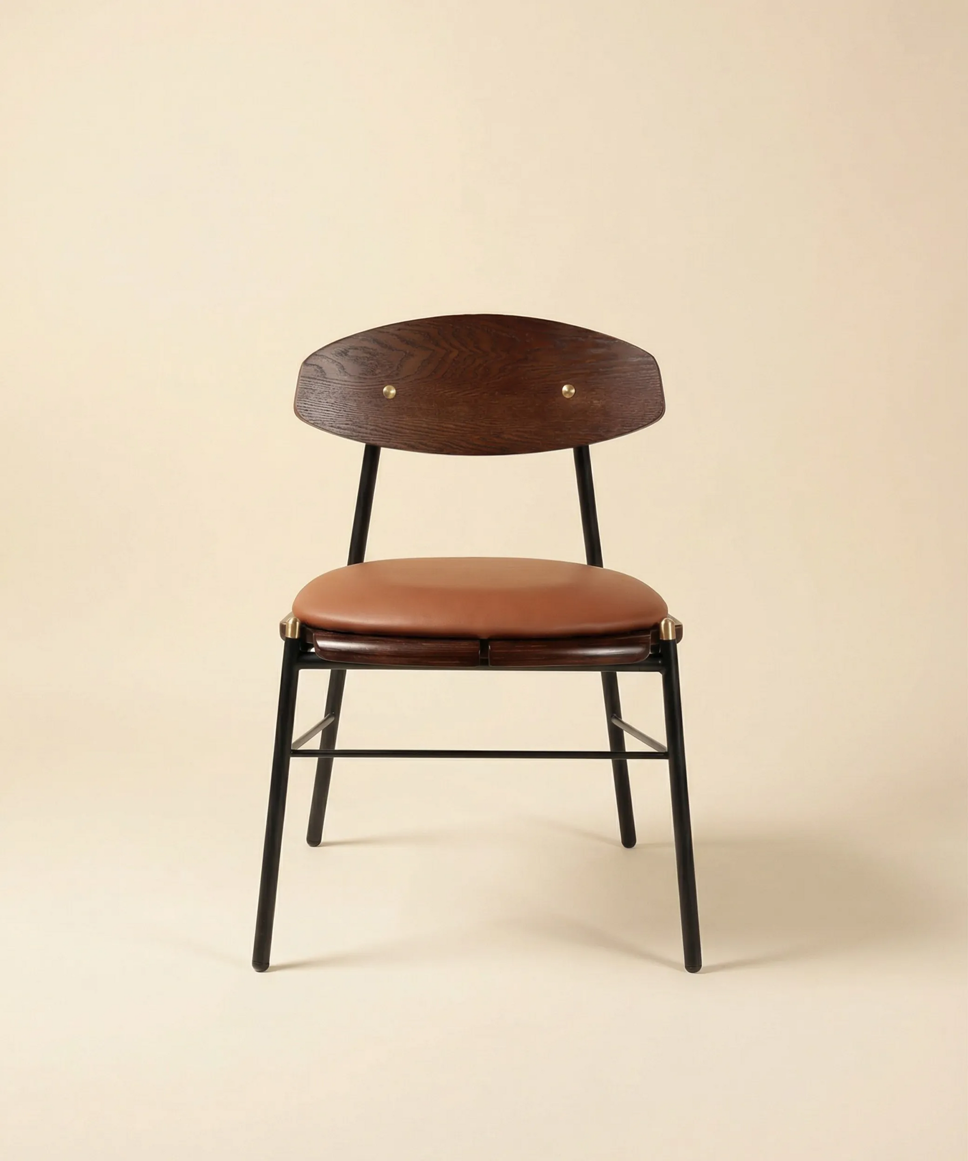 Silla Mocán con respaldo en madera de fresno tono oscuro y estructura metálica negra con asiento tapizado marrón.