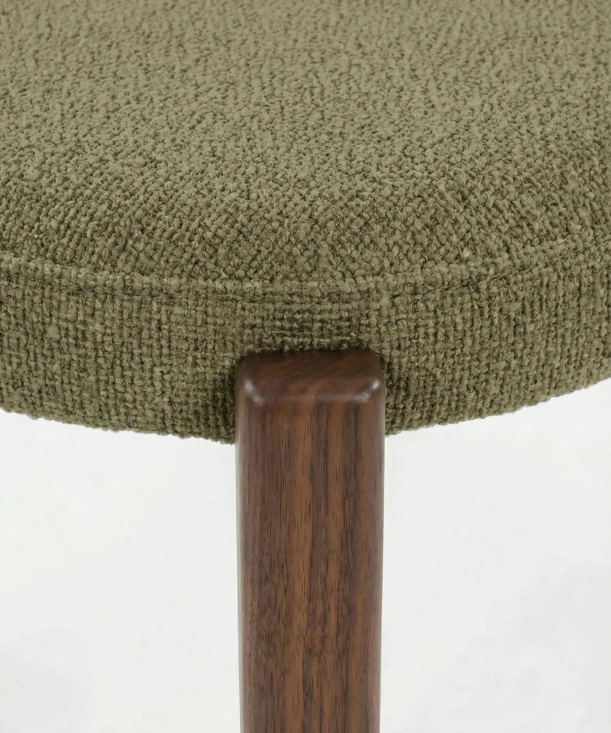 Detalle de la tela texturizada y pata de madera en silla Malpica de diseño contemporáneo y acabado natural