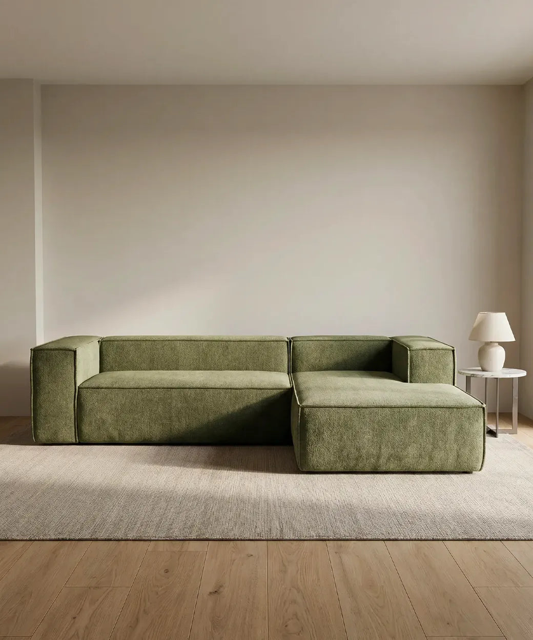 Sofá Cinchado en tono verde oliva con diseño geométrico y estructura modular sobre alfombra neutra en sala minimalista.
