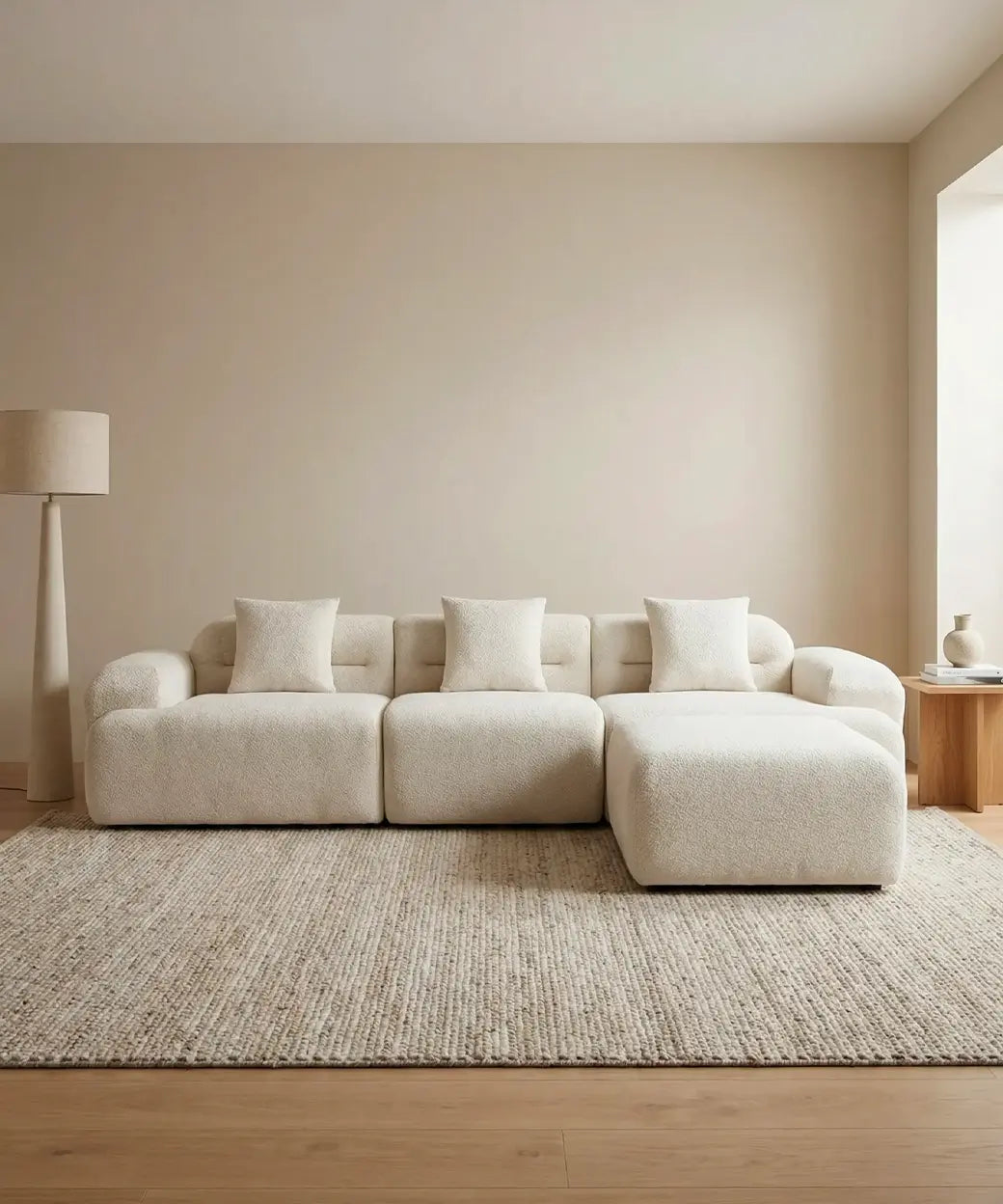 Haría en tono neutro con diseño modular y textura bouclé sobre alfombra de fibras naturales en ambiente sereno y luminoso