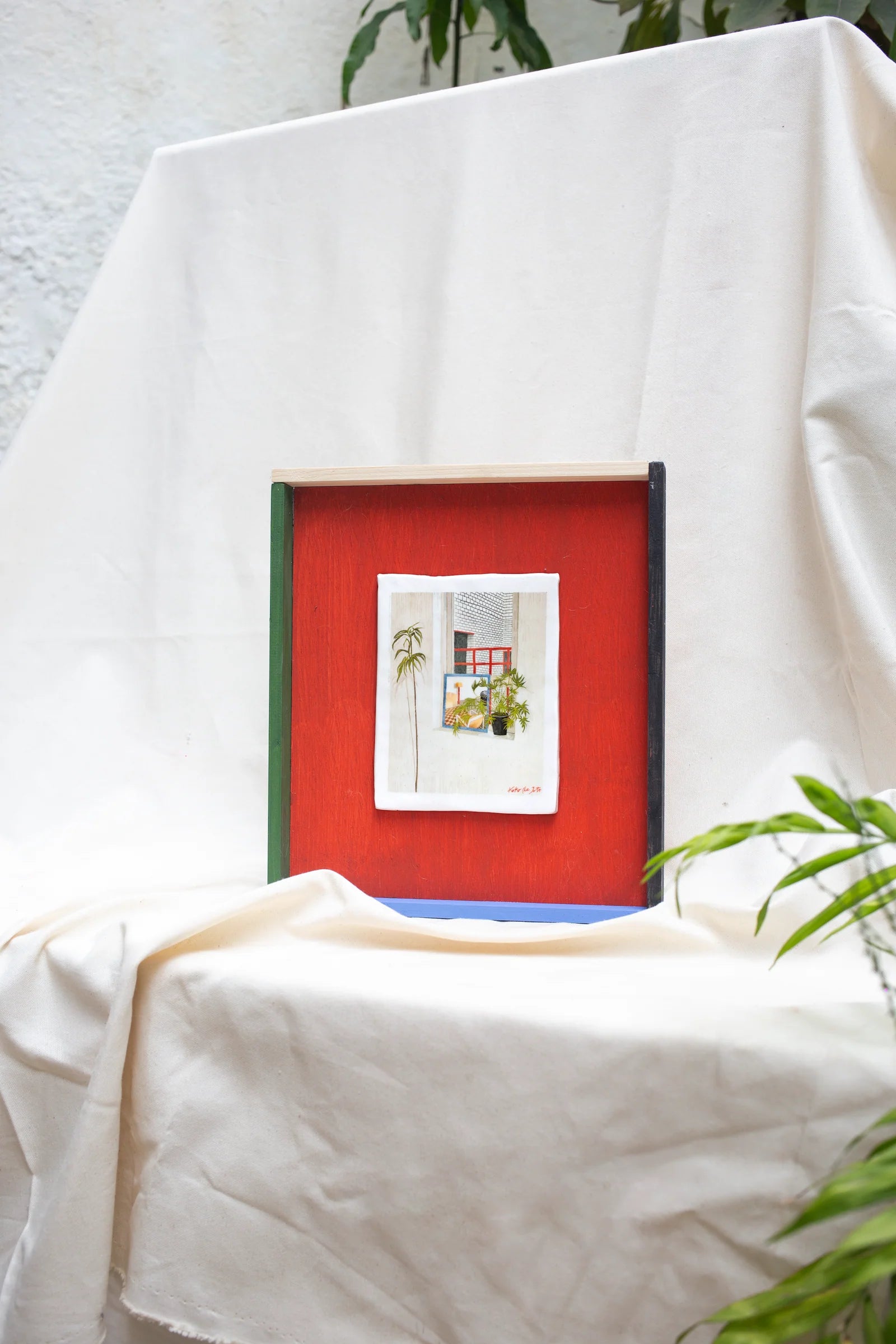 METACUADRO" // Cuadro de Cerámica con ventana y plantas, marco con colores rojo, azul y verde sobre fondo neutro.