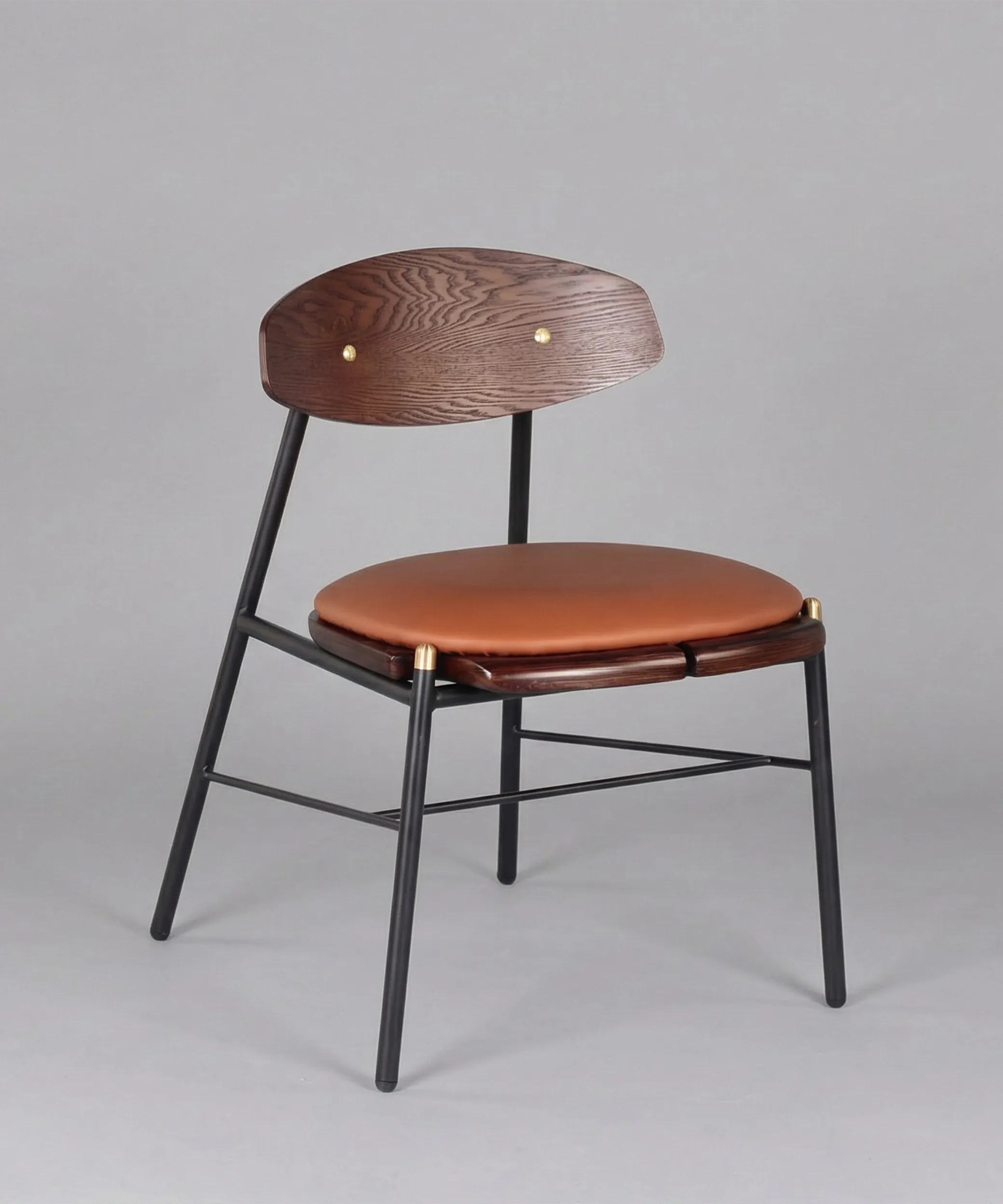 Silla Mocán con respaldo de madera de fresno y estructura metálica negra, diseño equilibrado y asiento acolchonado color cuero.