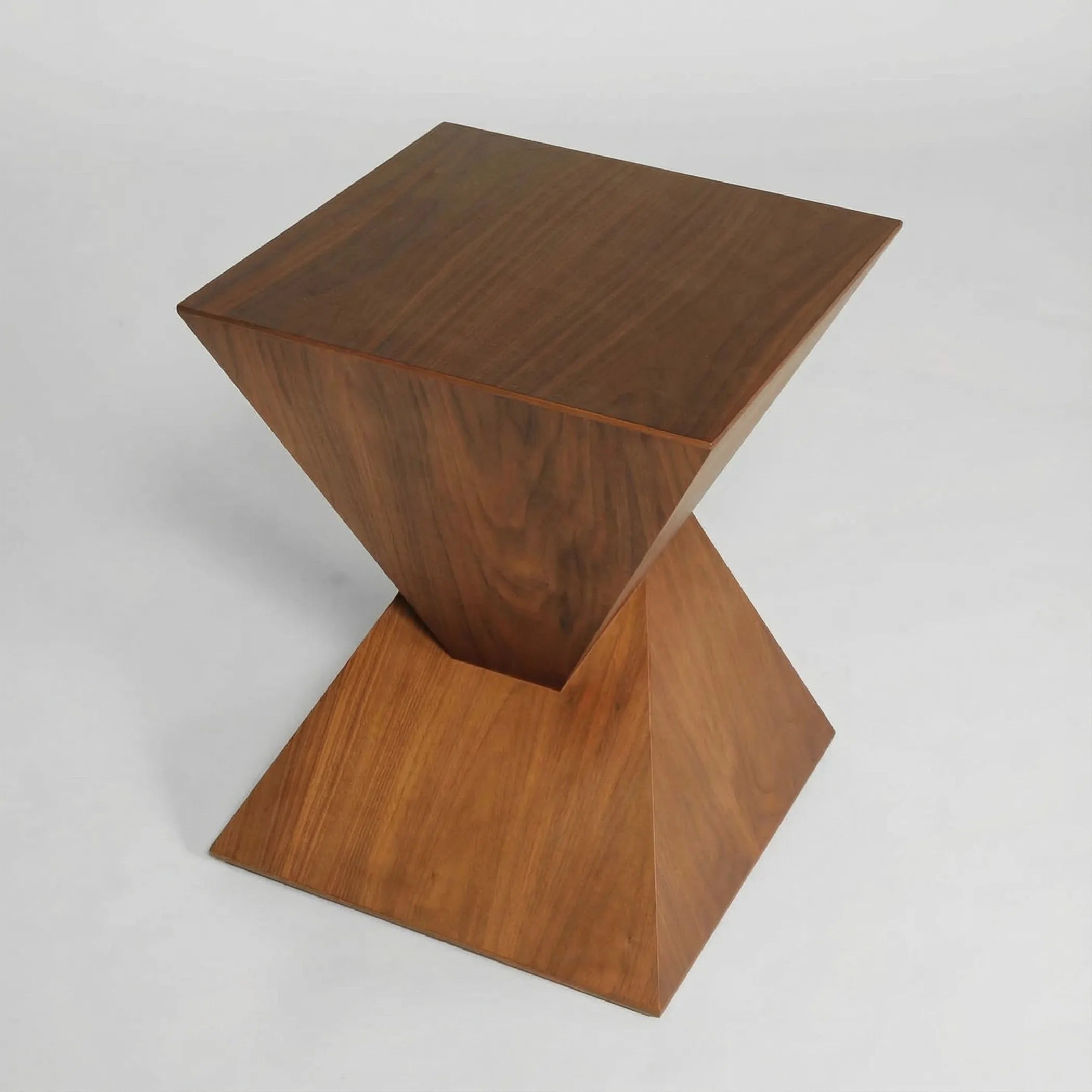 Mesa auxiliar Siroco en madera de fresno con diseño geométrico escultórico y presencia arquitectónica elegante.