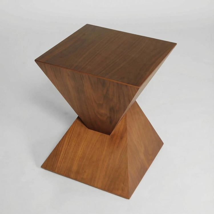 Mesa auxiliar Siroco en madera de fresno con diseño geométrico escultórico y presencia arquitectónica elegante.