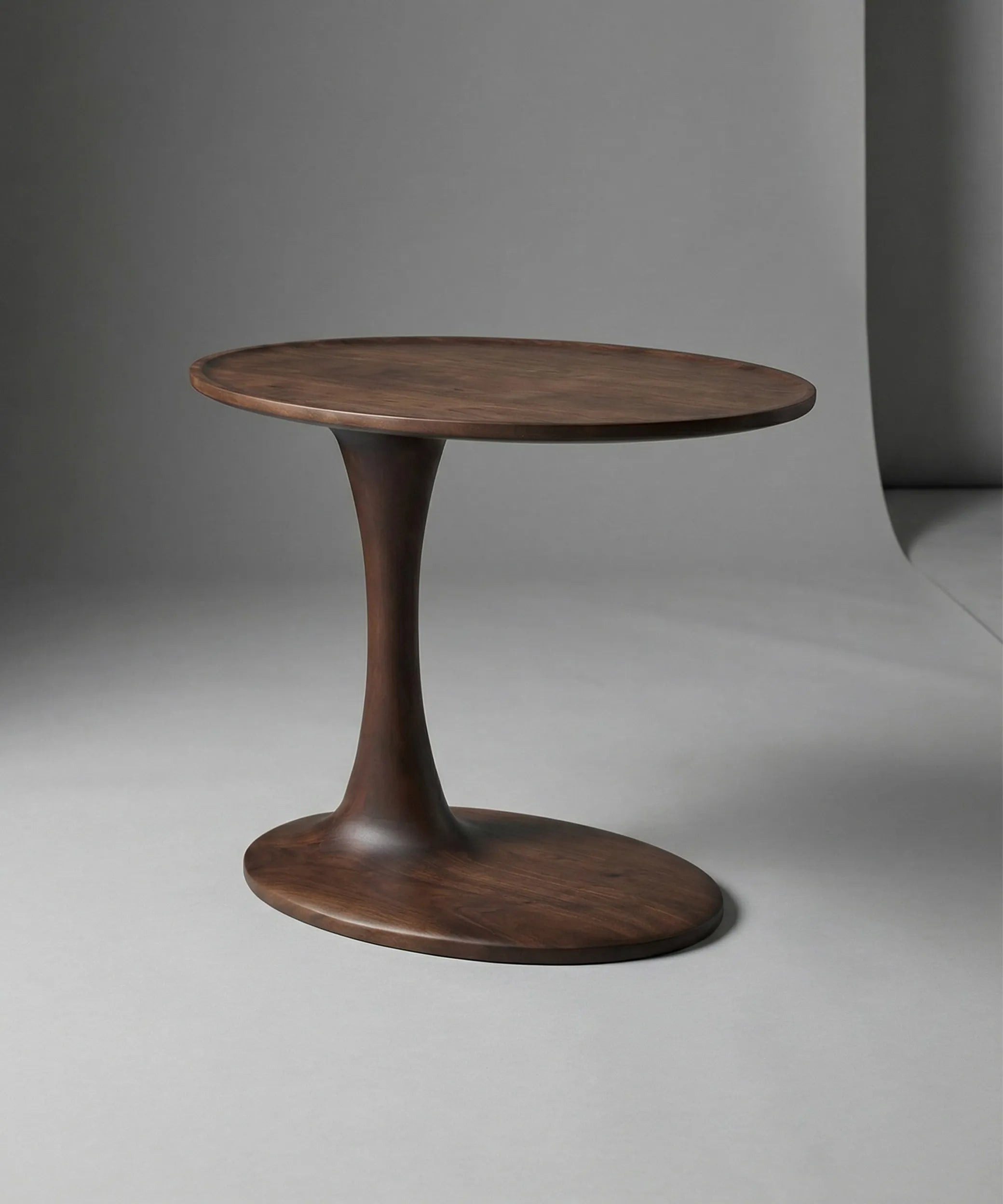 Mesa auxiliar Brisa en madera de fresno con acabado nogal oscuro y diseño escultórico para ambiente contemporáneo elegante