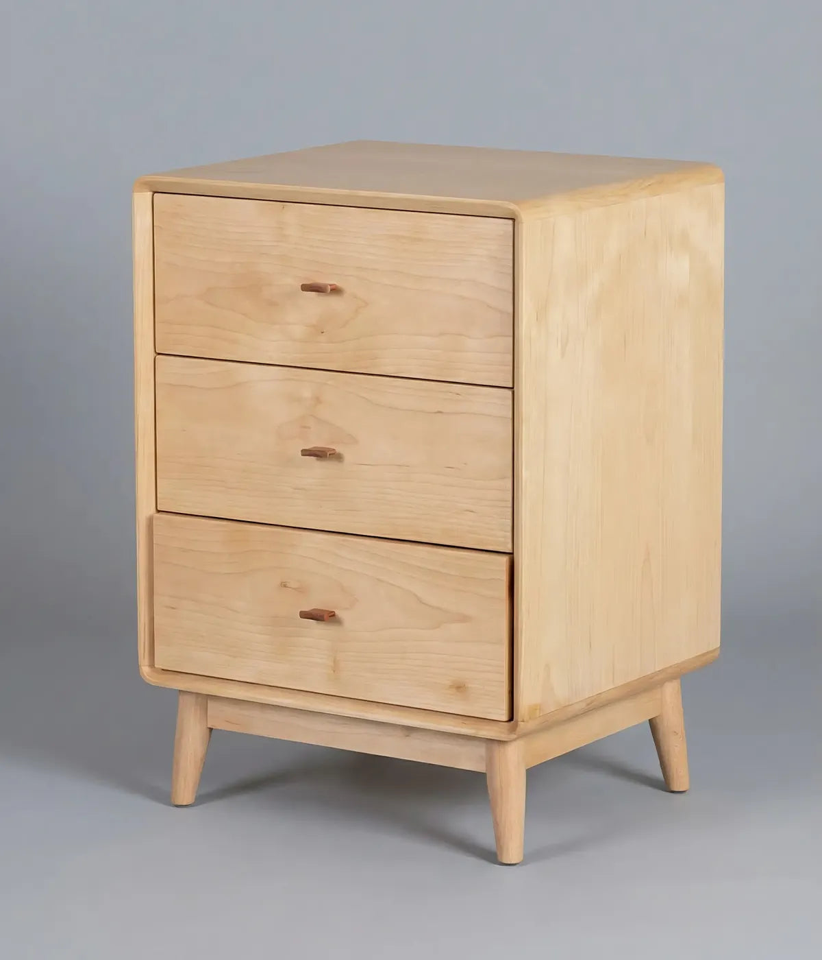 Mesa de noche Nogales en madera de fresno con tres cajones, diseño funcional y acabado natural elegante.