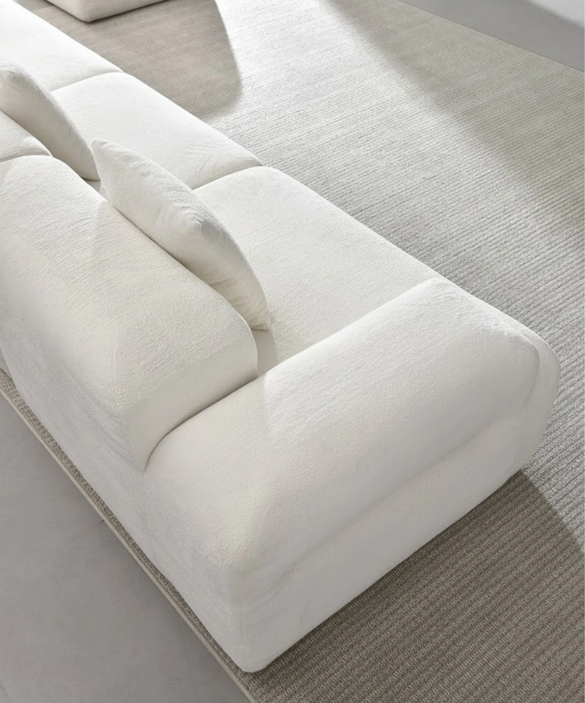 Sofá modular Haría en tono blanco con diseño cómodo y moderno sobre alfombra gris claro en espacio minimalista.