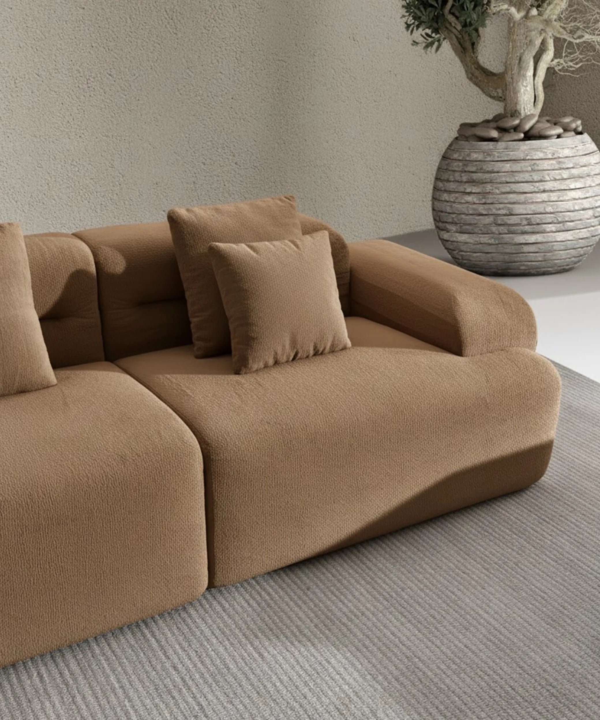 Sofá modular Haría color beige con cojines cómodos en sala de estar moderna junto a maceta decorativa.