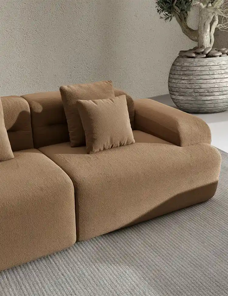 Sofa modular de compresion beige oscuro en salon claro con una planta decorativa y una alfombra blanca