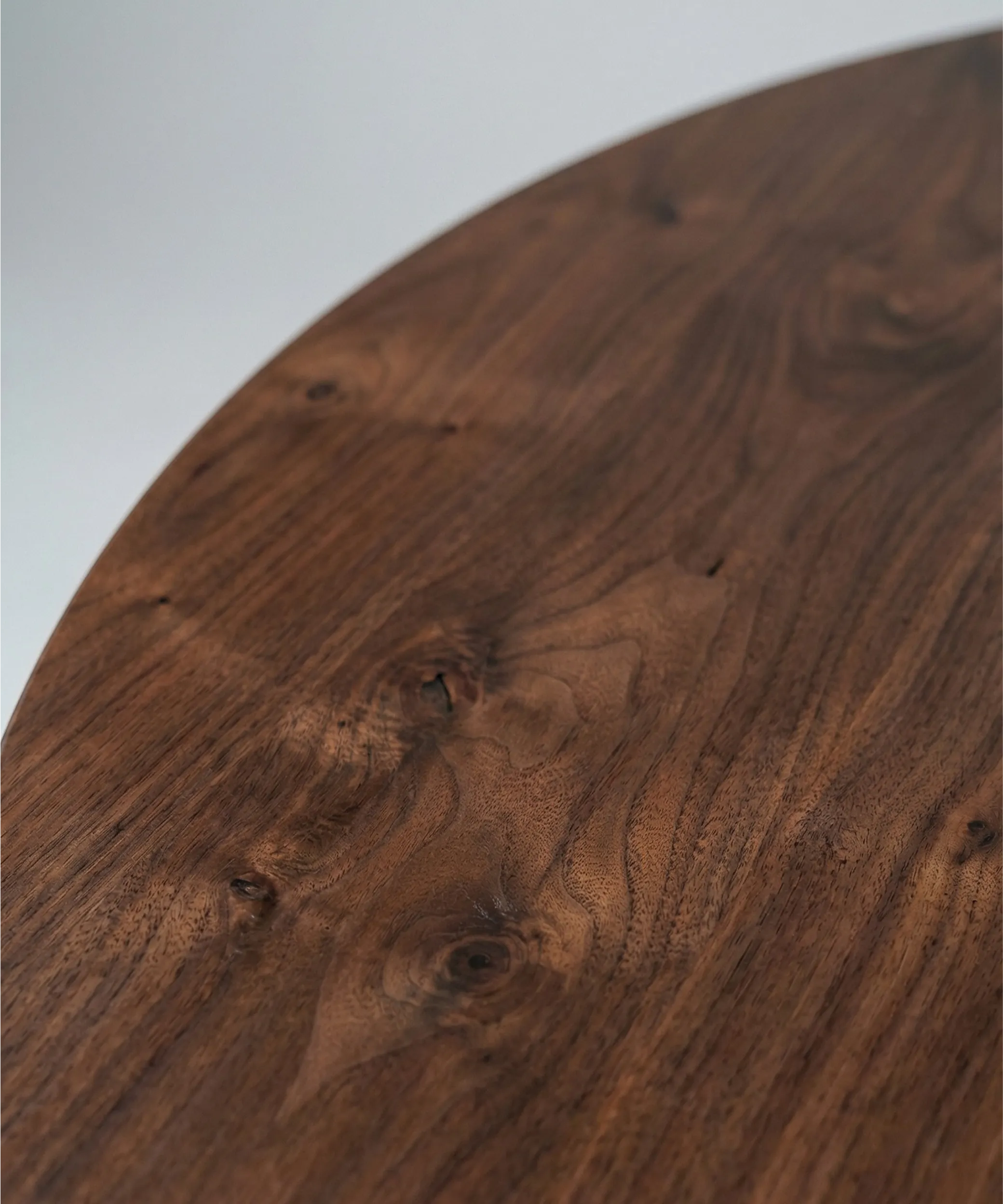 Superficie de madera oscura con vetas y nudos visibles, mostrando textura natural y acabado pulido suave.
