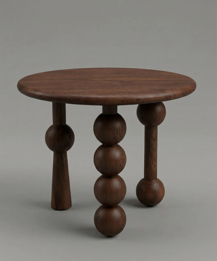 Mesa auxiliar Niebla en madera de fresno tono café con diseño escultórico y patas esféricas distintivas.