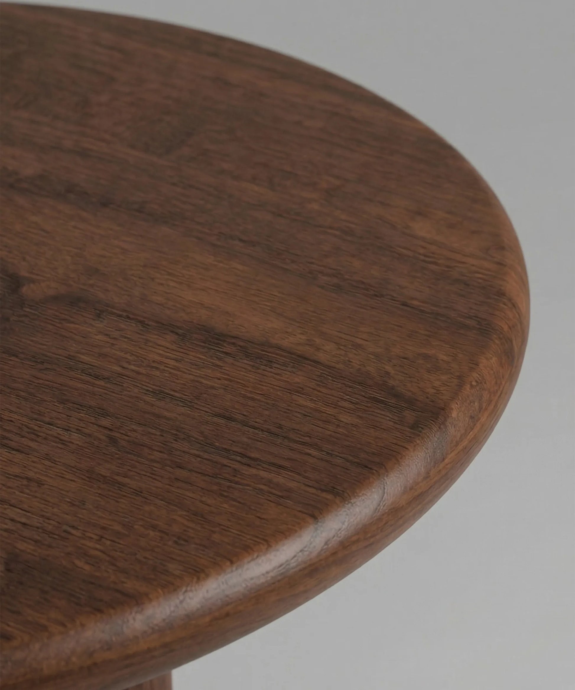 Mesa auxiliar Niebla en madera de fresno color café con diseño escultórico y acabado suave y natural.