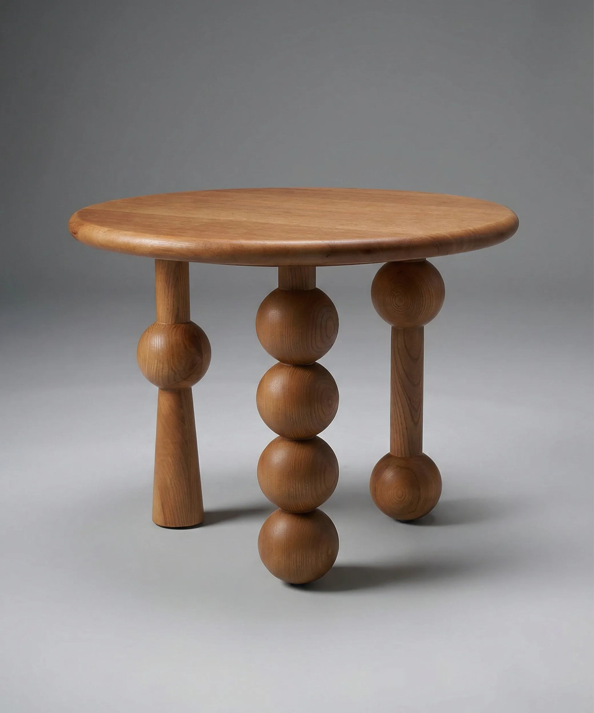 Mesa auxiliar Niebla en madera de fresno tono café con diseño escultórico y patas esféricas para ambiente moderno y artístico.