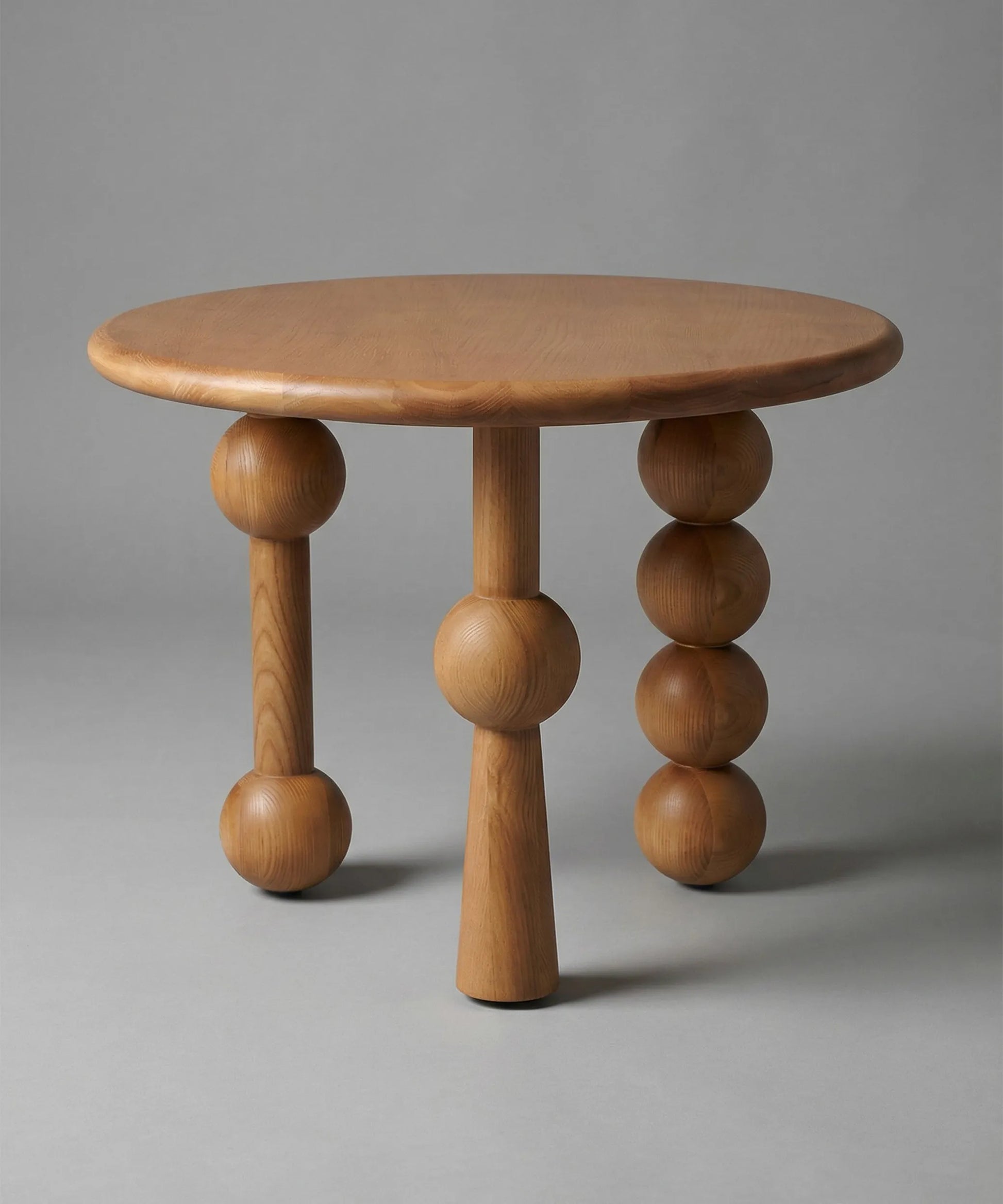 Mesa auxiliar Niebla en madera de fresno tono natural con diseño escultórico y moderno para espacios elegantes y acogedores.