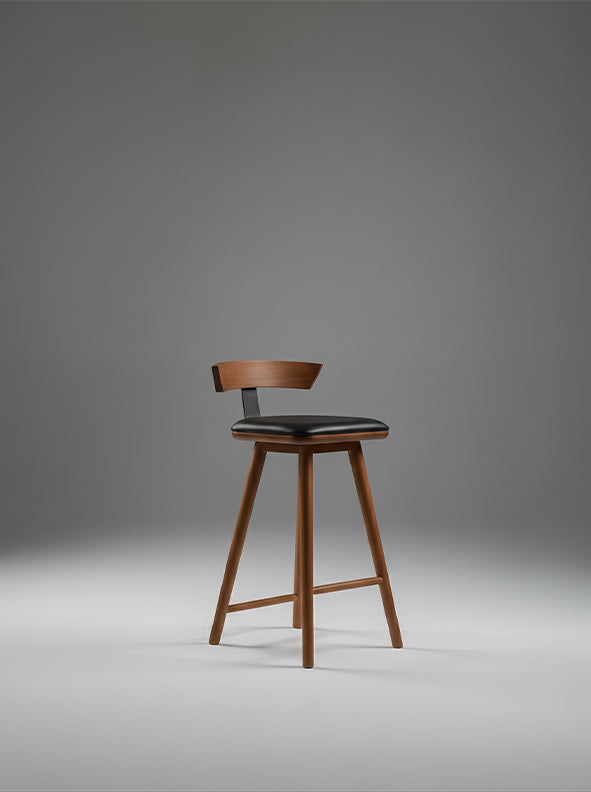 Taburete Morrojable con respaldo curvo en madera de fresno café y asiento acolchonado negro, diseño contemporáneo y natural.