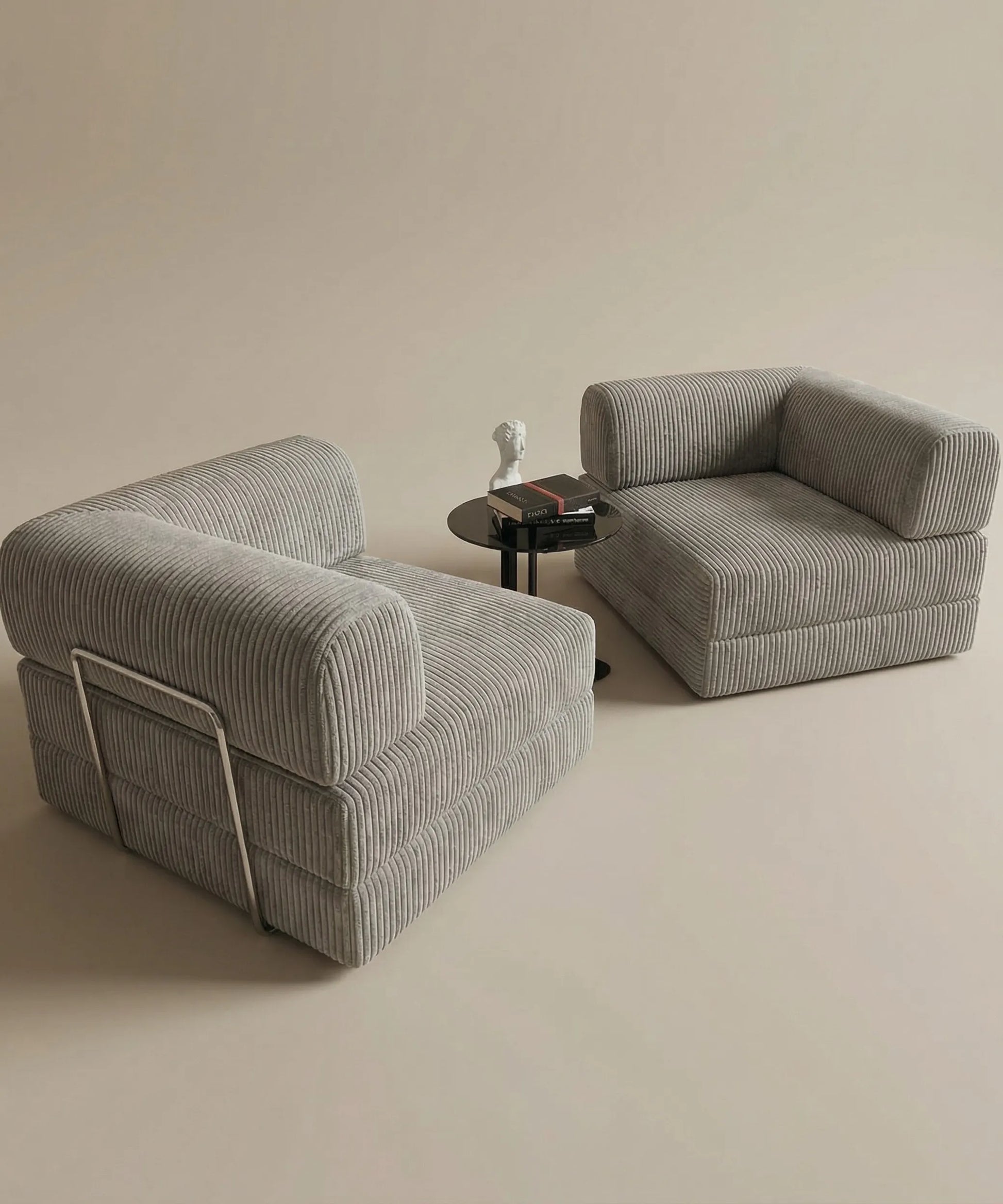 Sillones modulares Alisios en tela rayada gris con mesa lateral negra y decoración minimalista sobre fondo neutro